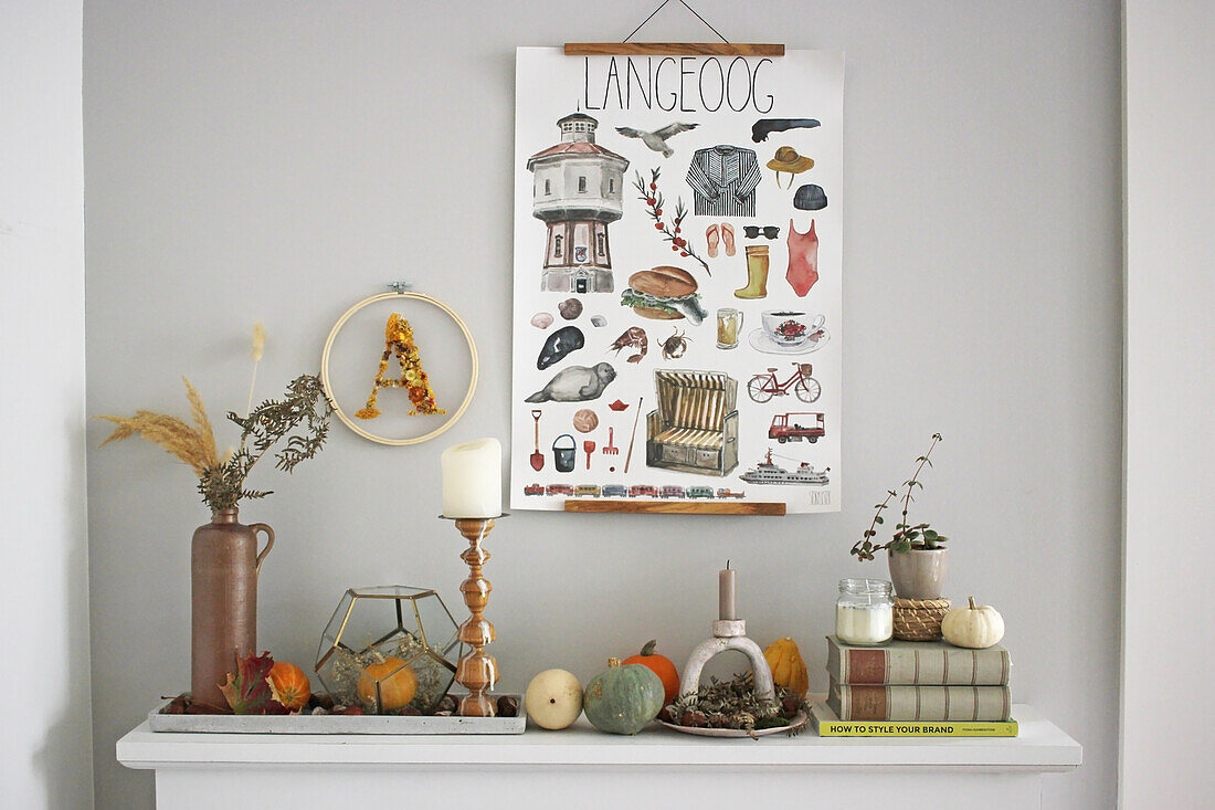 Herbstliche Dekoration mit Zierkürbissen auf Kaminsims, darüber illustriertes Poster