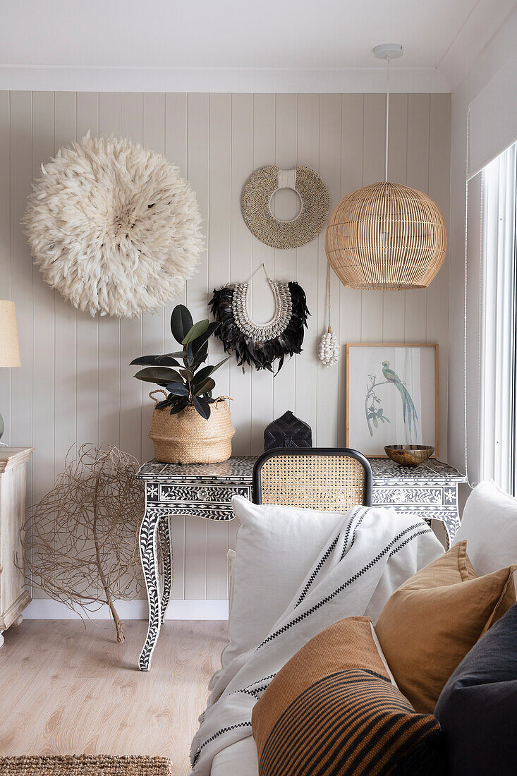 Sofa mit Kissen, und Schreibtisch mit Perlmutt-Intarsien, darüber Juju-Hut an der Wand
