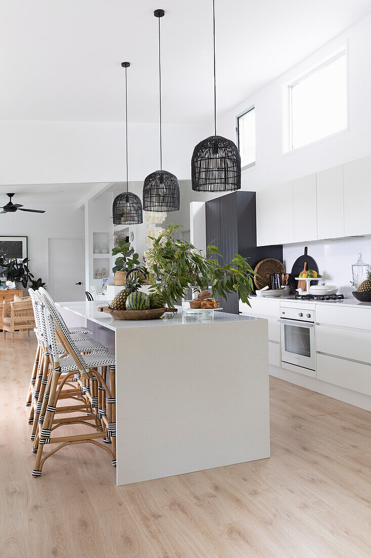 Kitchen island with bar stools and black pendant lights in open-plan kitchen