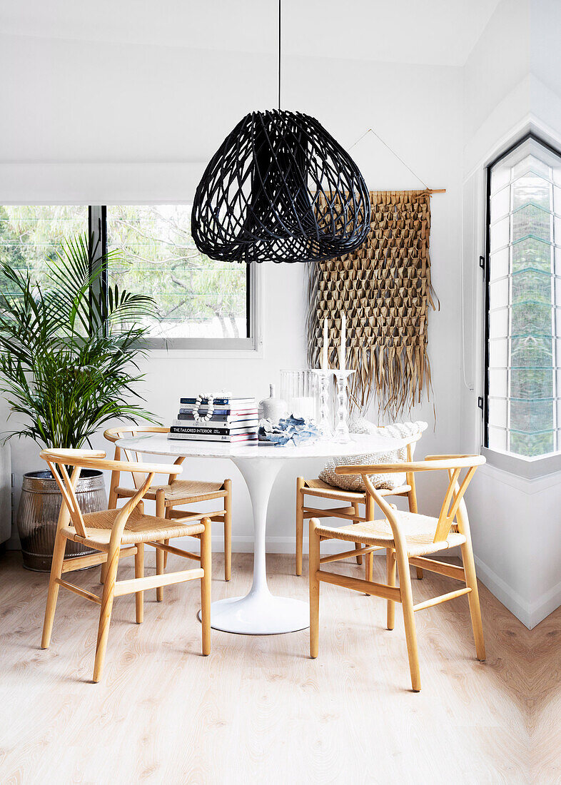 Round table with rattan chairs and black rattan lamp in a light room