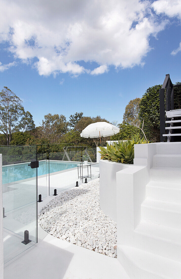 Terrace with white steps and pool behind glass partition