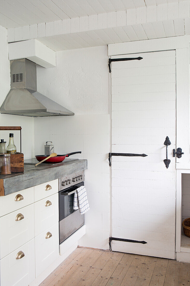 Weiße Küchenzeile mit robuster Arbeitsplatte und Speisekammer hinter der Tür