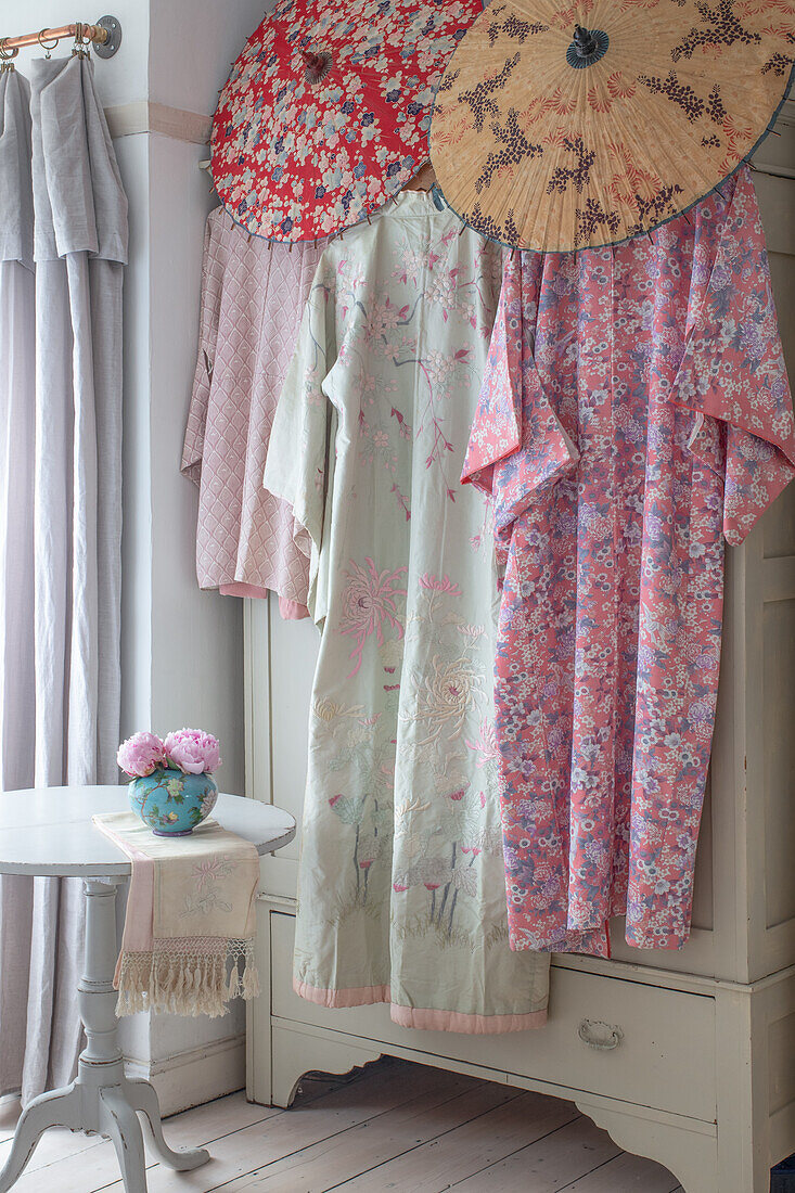 Vintage Sonnenschirme und Kimonos hängen am Kleiderschrank