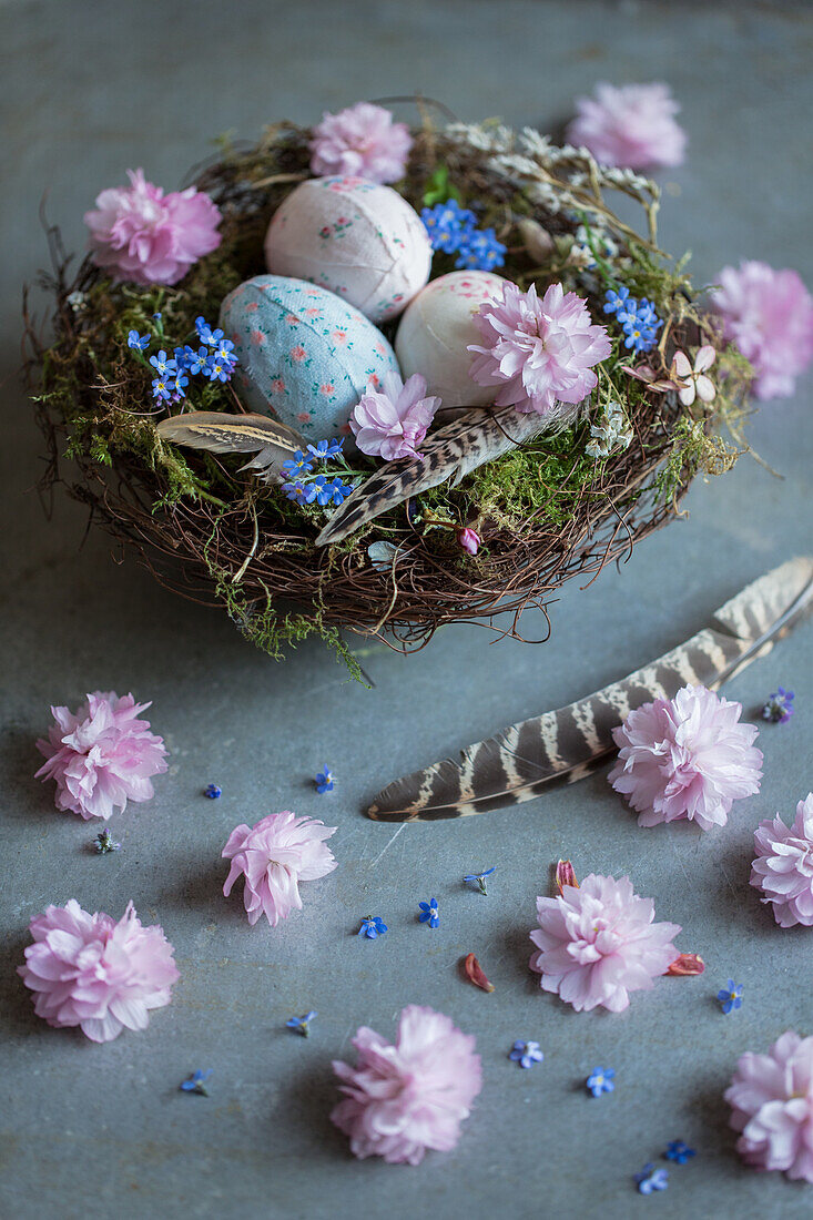 Mit Stoff bezogene DIY-Ostereier und Blüten im Nest