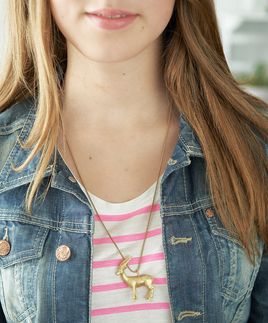 Girl wearing necklace with reindeer figurine as pendant