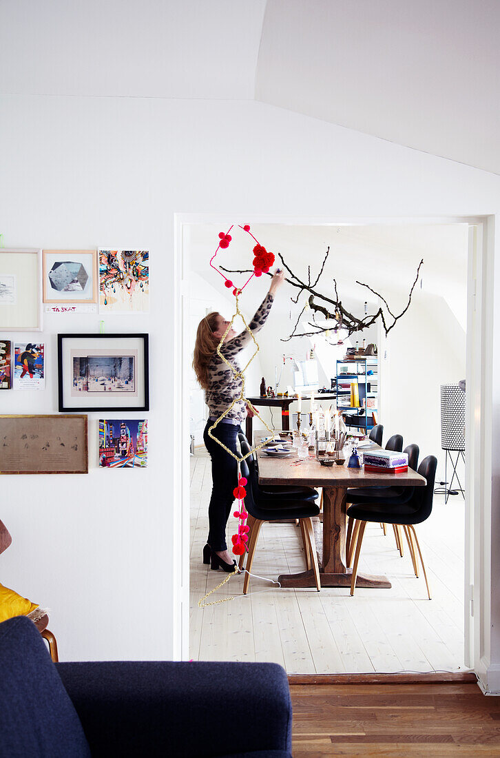 Woman decorates branches above dining table