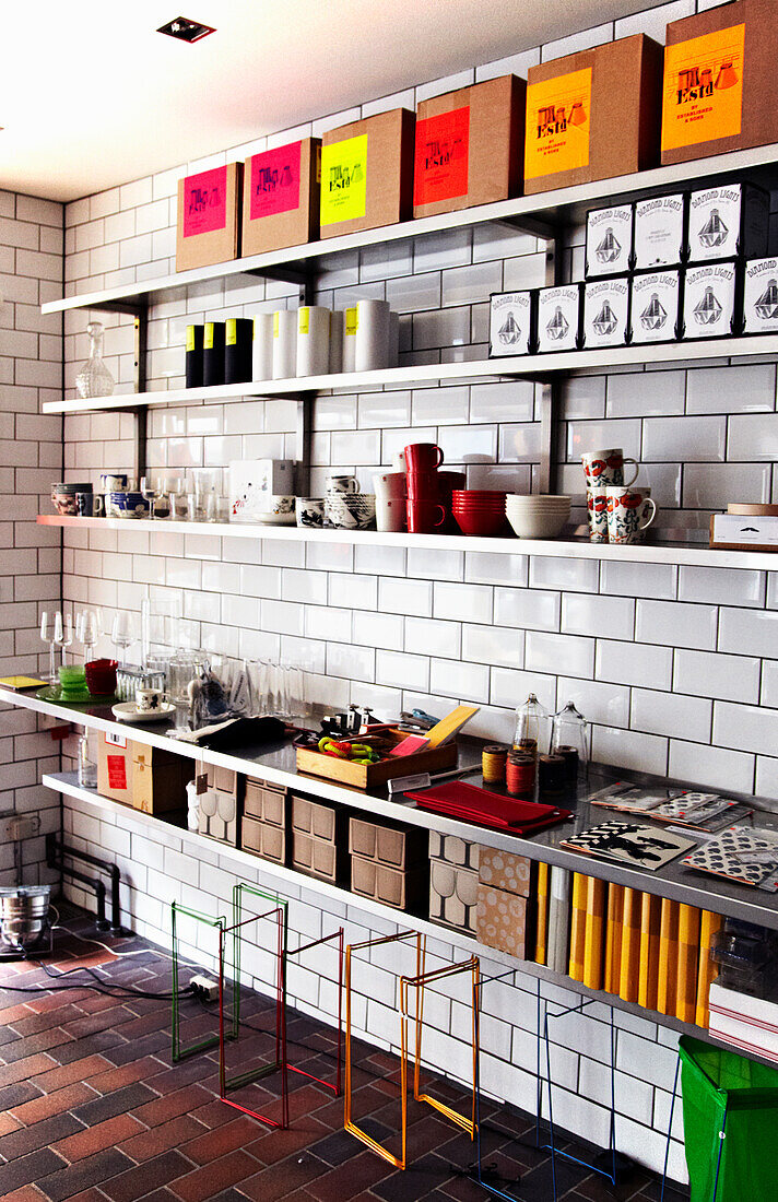 Modern shelves with crates, boxes and crockery on a white tiled wall