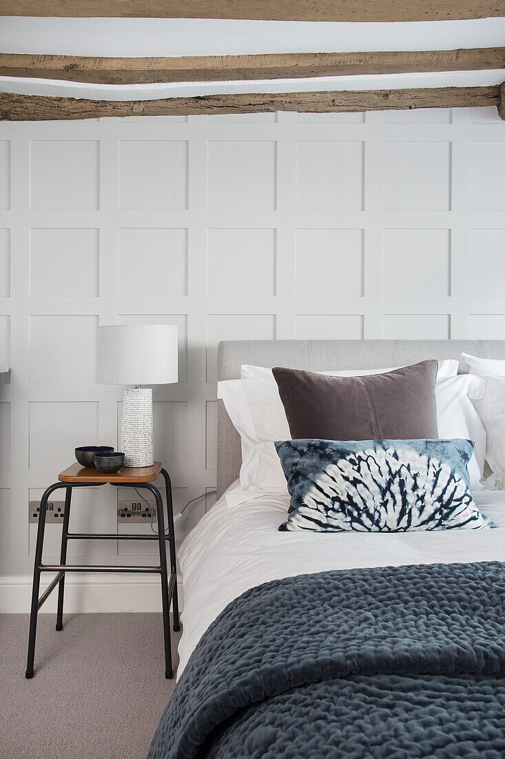 Double bed in the guest bedroom with white panelled wall and wood-beamed ceiling