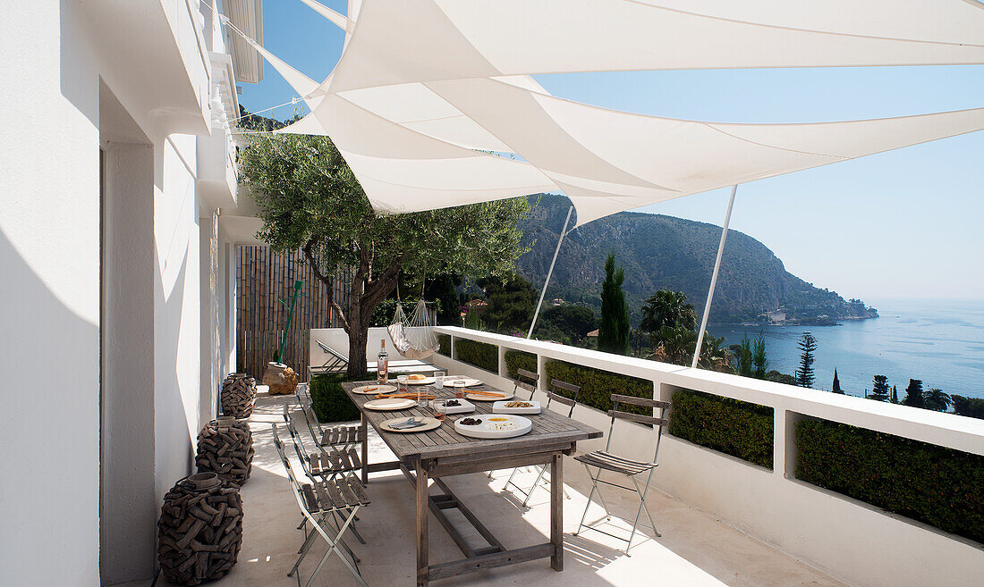 Gedeckter Tisch auf der Terrasse mit Sonnensegeln an der französischen Riviera