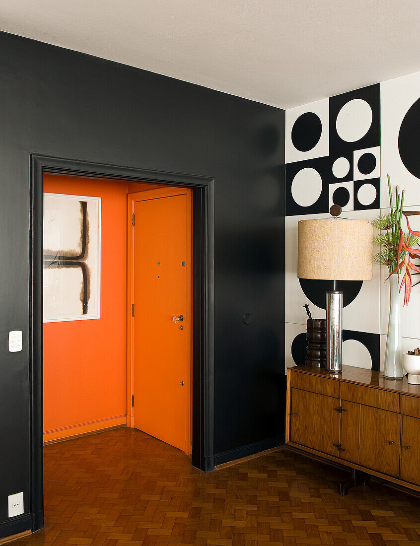 Appartement im 60er-Jahre Stil, mit schwarzer Wand und orangefarbenem Eingangsbereich