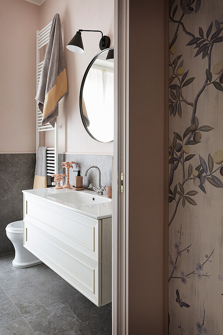 White washstand in bathroom with pink walls and grey floor tiles