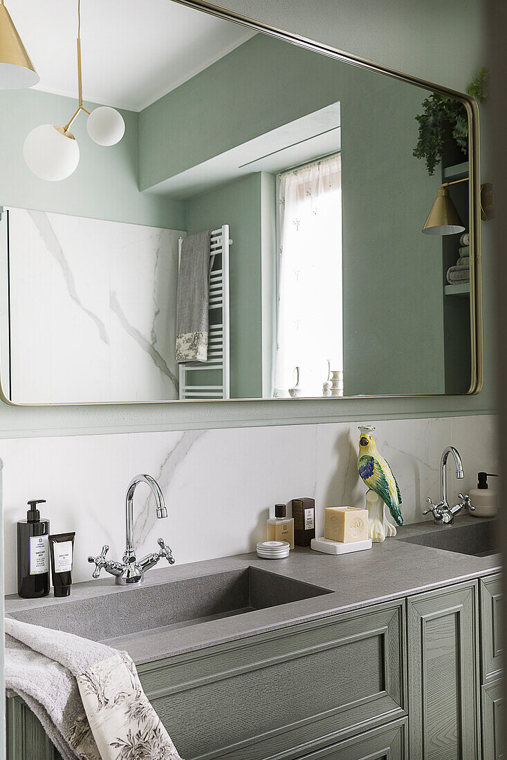 Waschtisch und Spiegel im Badezimmer mit grünen Wänden