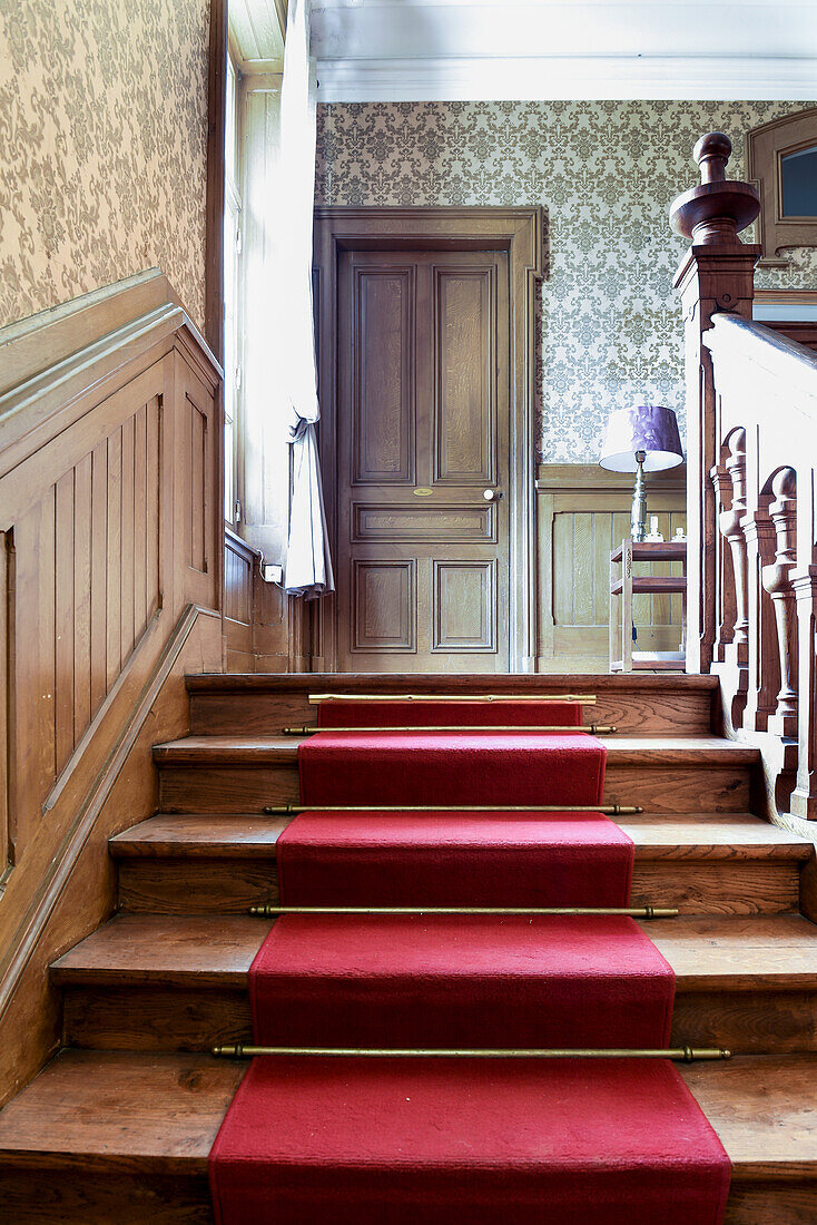 Old wooden staircase with red carpet