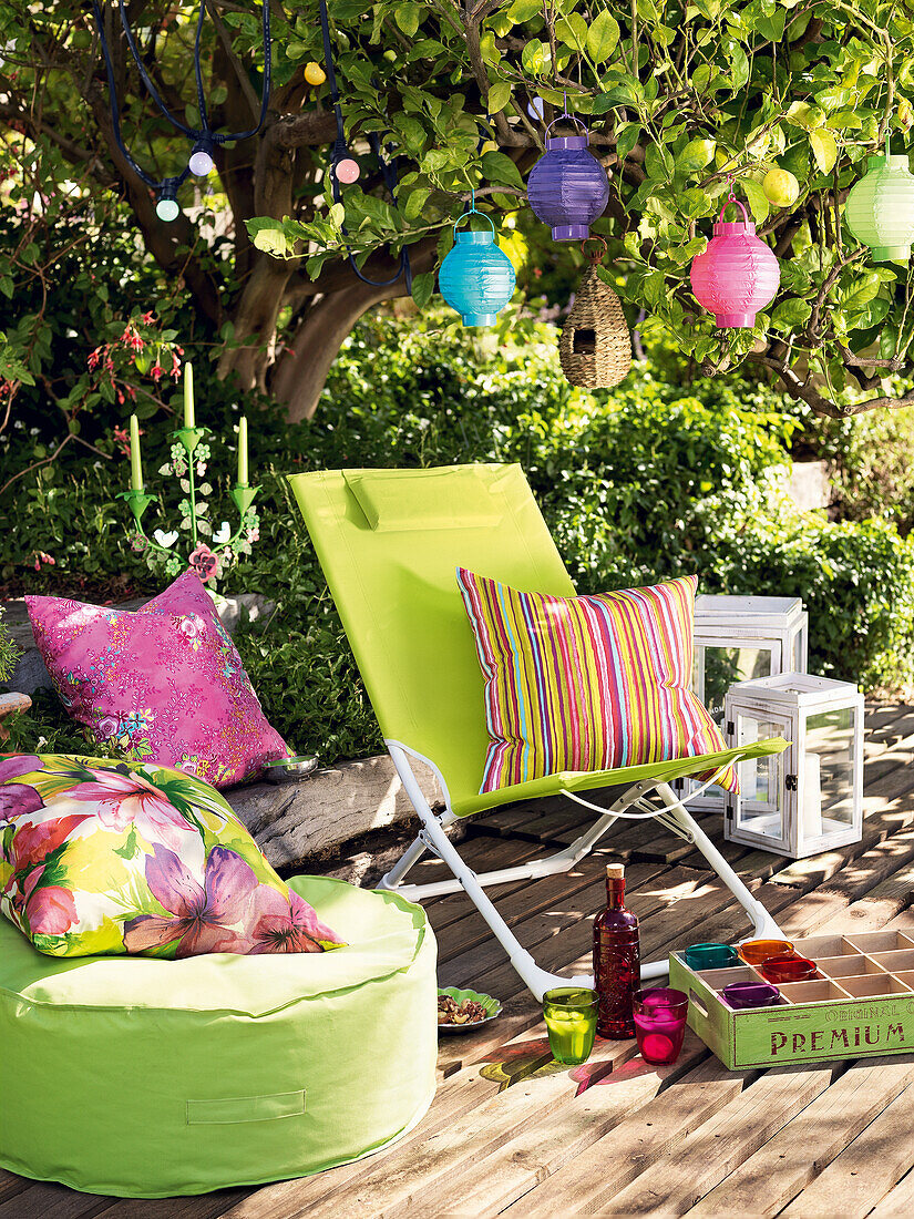 Liegestuhl, Sitzkissen, Kissen, Laternen und Lampions auf sommerlicher Terrasse