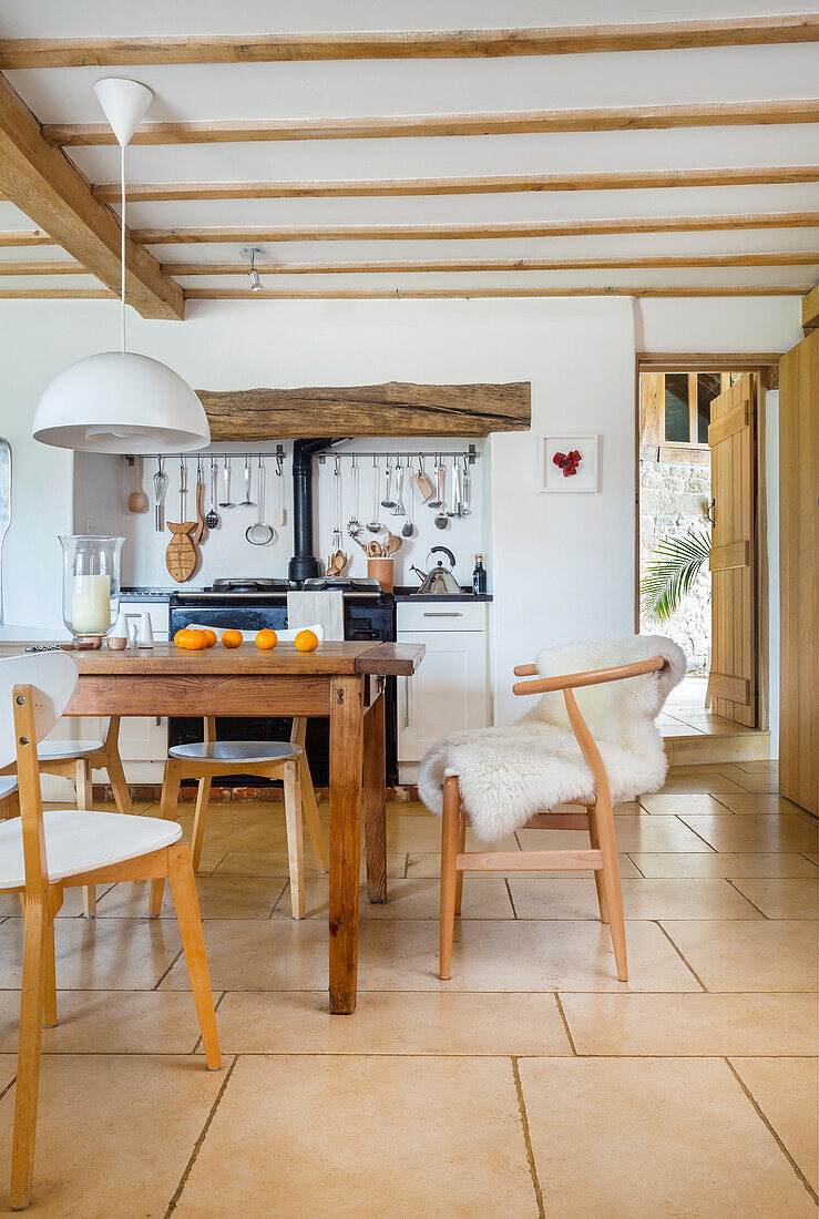 White eat-in kitchen with wooden dining table and classic chairs in a converted barn