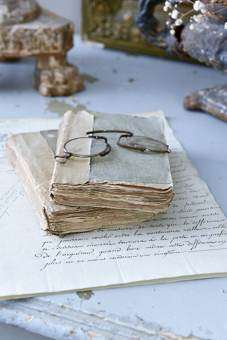 Pince-nez on battered old books and handwritten letter