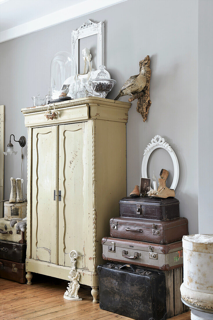Stack of old suitcases next to old cupboard with vintage-style decorations