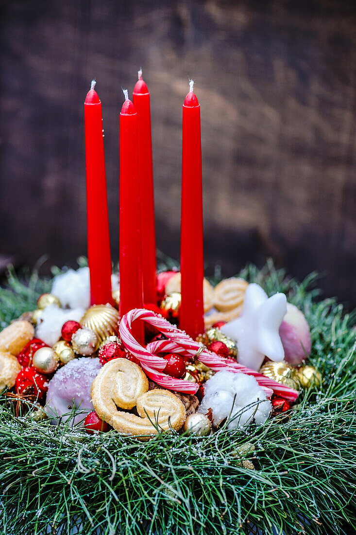 Weihnachtskranz mit Süssigkeiten und roten Kerzen