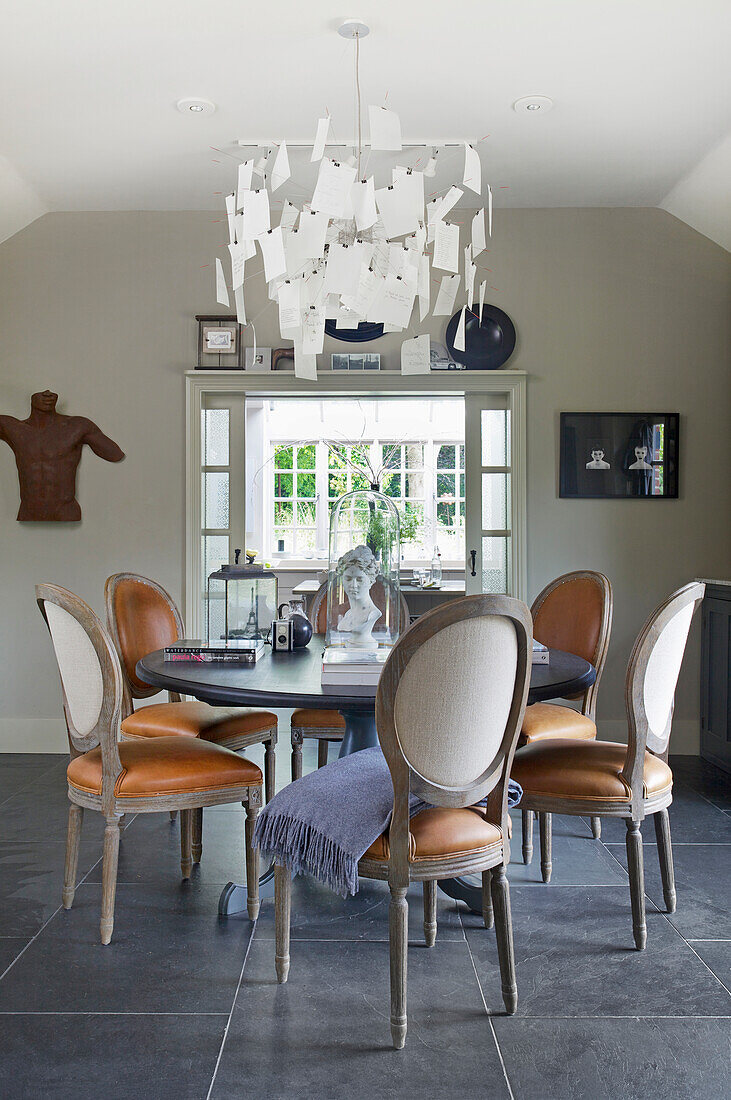 Wooden dining table and chairs with leather seats, above classic chandelier