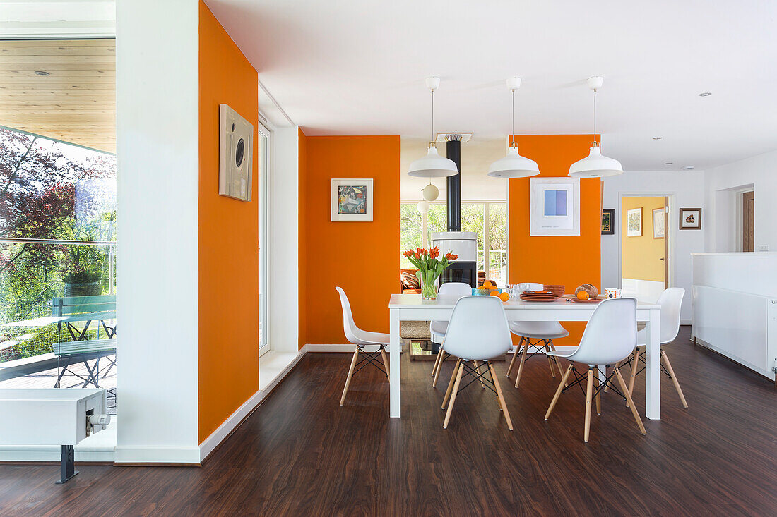 Weißer Tisch und Stühle im Essbereich mit orangefarbenen Wänden