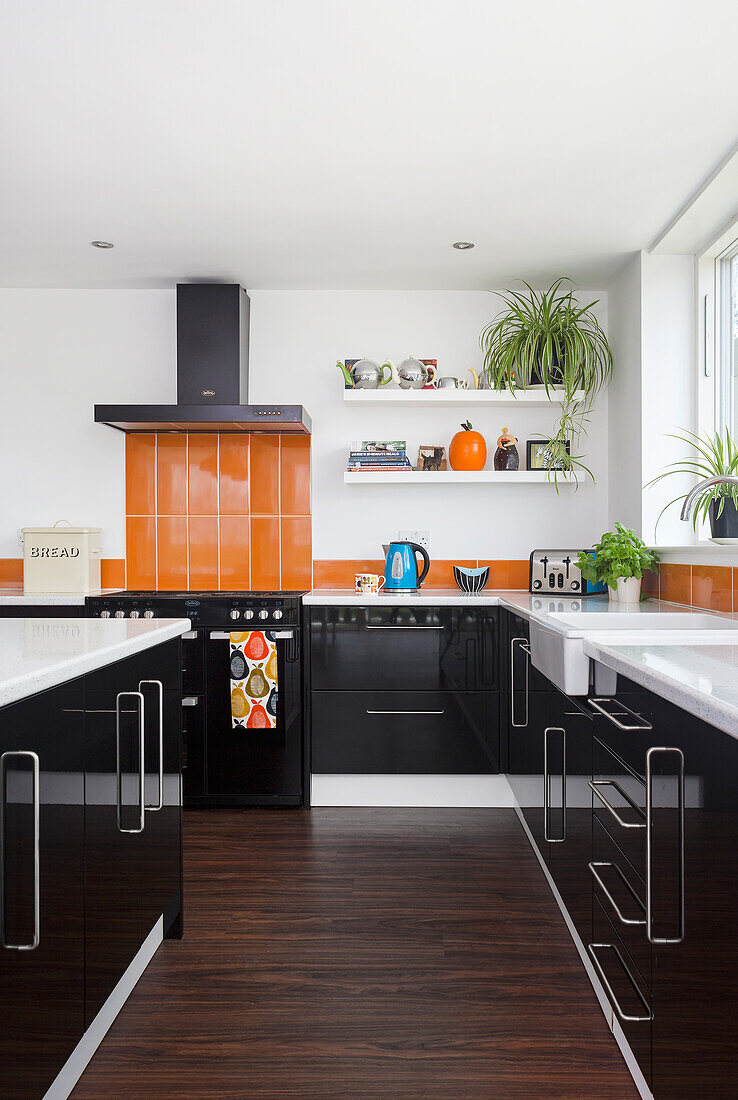 Fitted kitchen cabinets with black cupboard fronts and orange backsplash