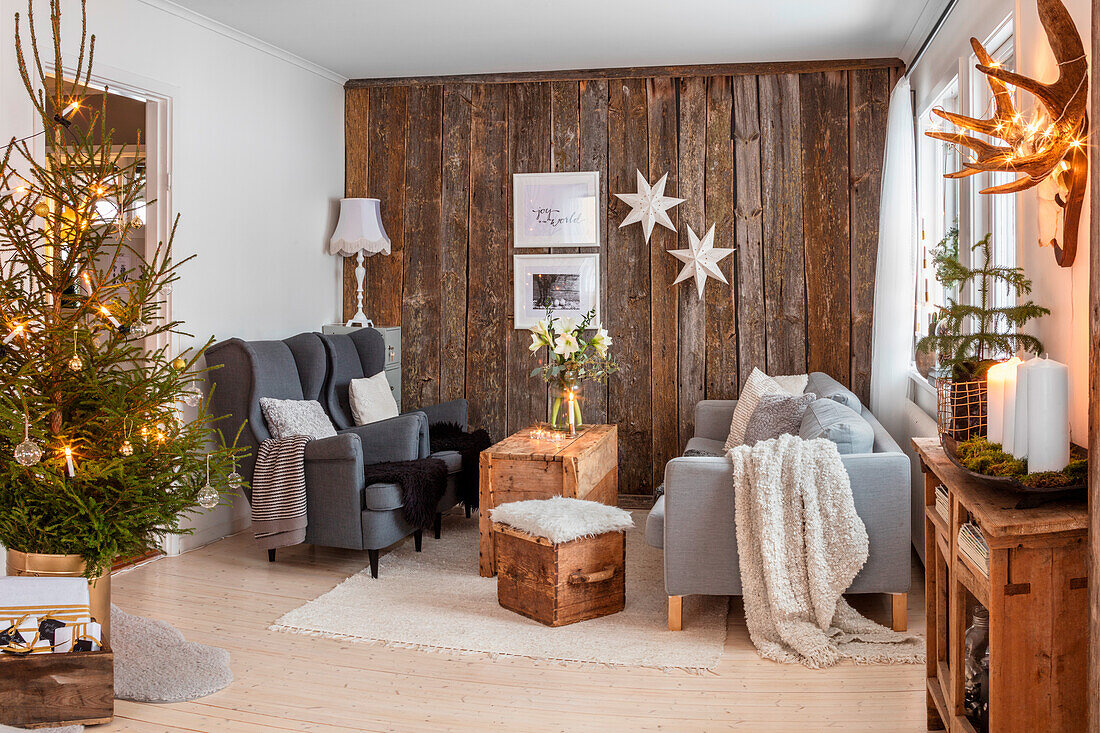 Weihnachtlich geschmücktes Wohnzimmer mit Holzakzentwand und Tannenbaum