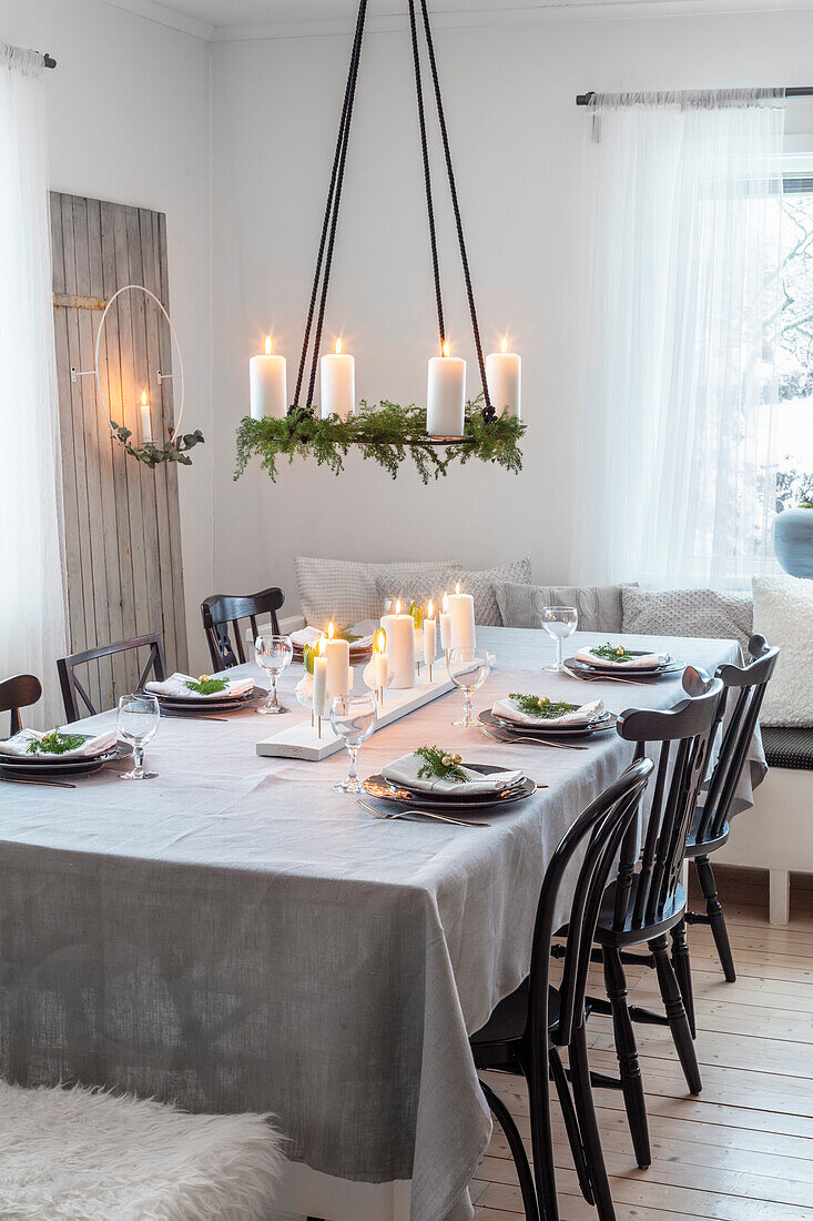 Dining table with festive decorations and pendant light with candles