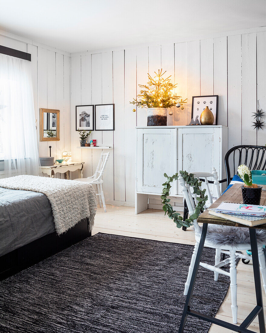 Schlafzimmer mit weißer Holzvertäfelung und verschiedenen Sitzmöglichkeiten
