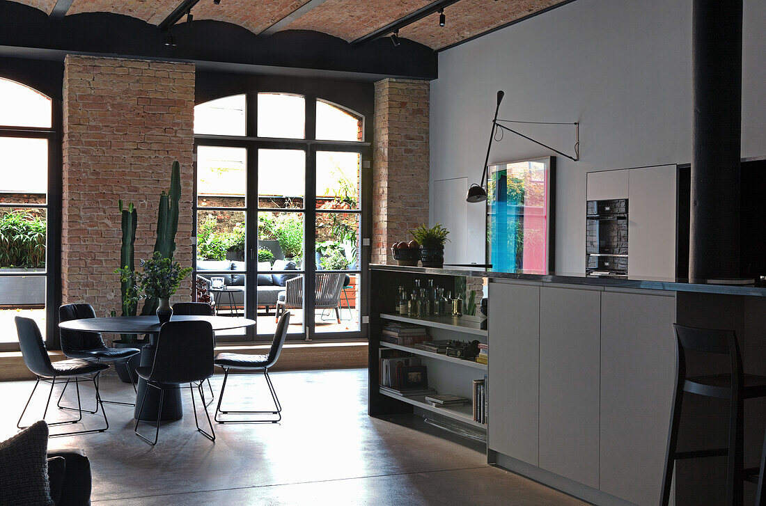 Loft kitchen with brick wall, black metal beams and terrace access