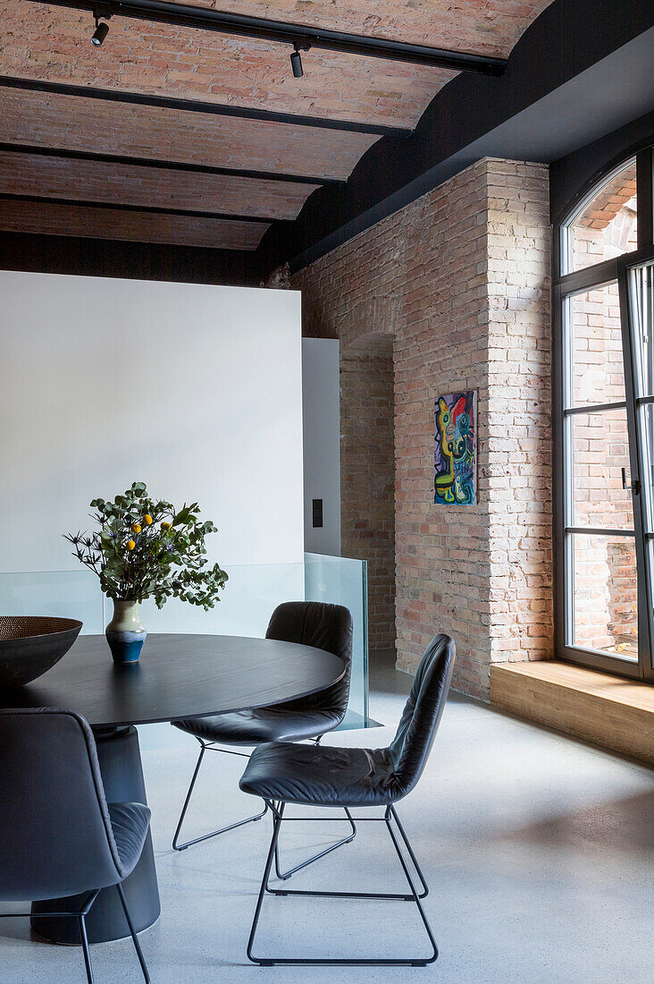 Dining table with black chairs and industrial-style brick wall