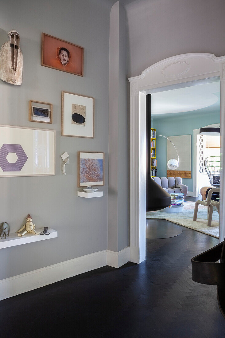 Hallway with dark floor and gallery wall, view into the living room