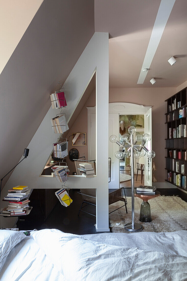 Pink-painted attic bedroom with bookshelves