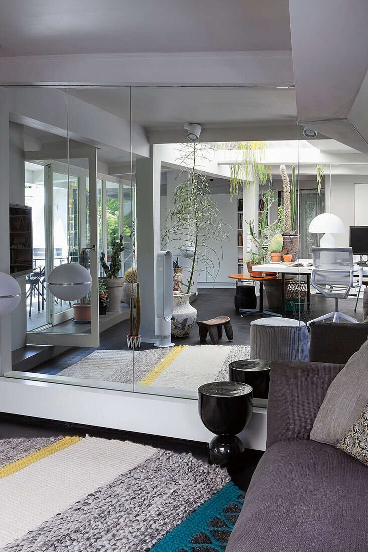 Mirror wall in living room with grey sofa and carpet with stripes