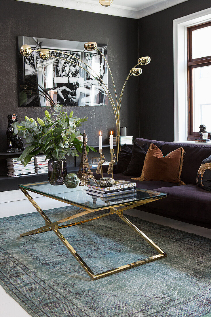 Living room with dark walls and glass coffee table with golden frame