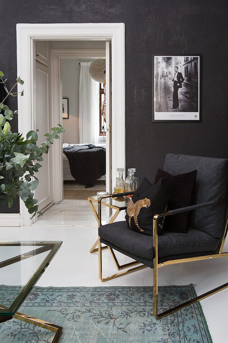 Black velvet armchair with gold frame in a living room with dark walls