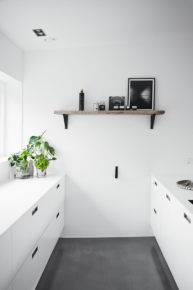 Minimalistische Küche in Weiß mit grauem Betonboden