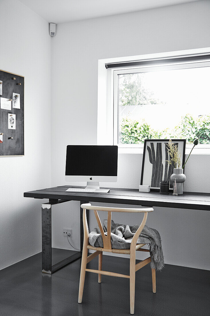 Designerstuhl am Schreibtisch im monochromen Arbeitszimmer