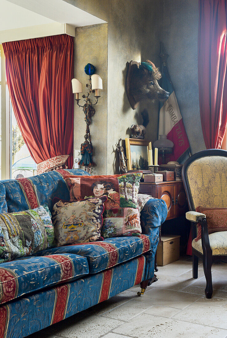 Patchwork cushions on blue and red sofa in vintage-style living room with flea-market finds