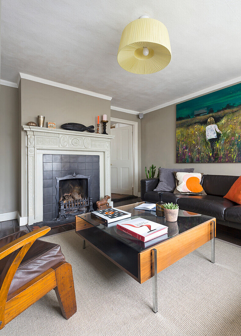 Living room with fireplace, black leather sofa and colorful mural