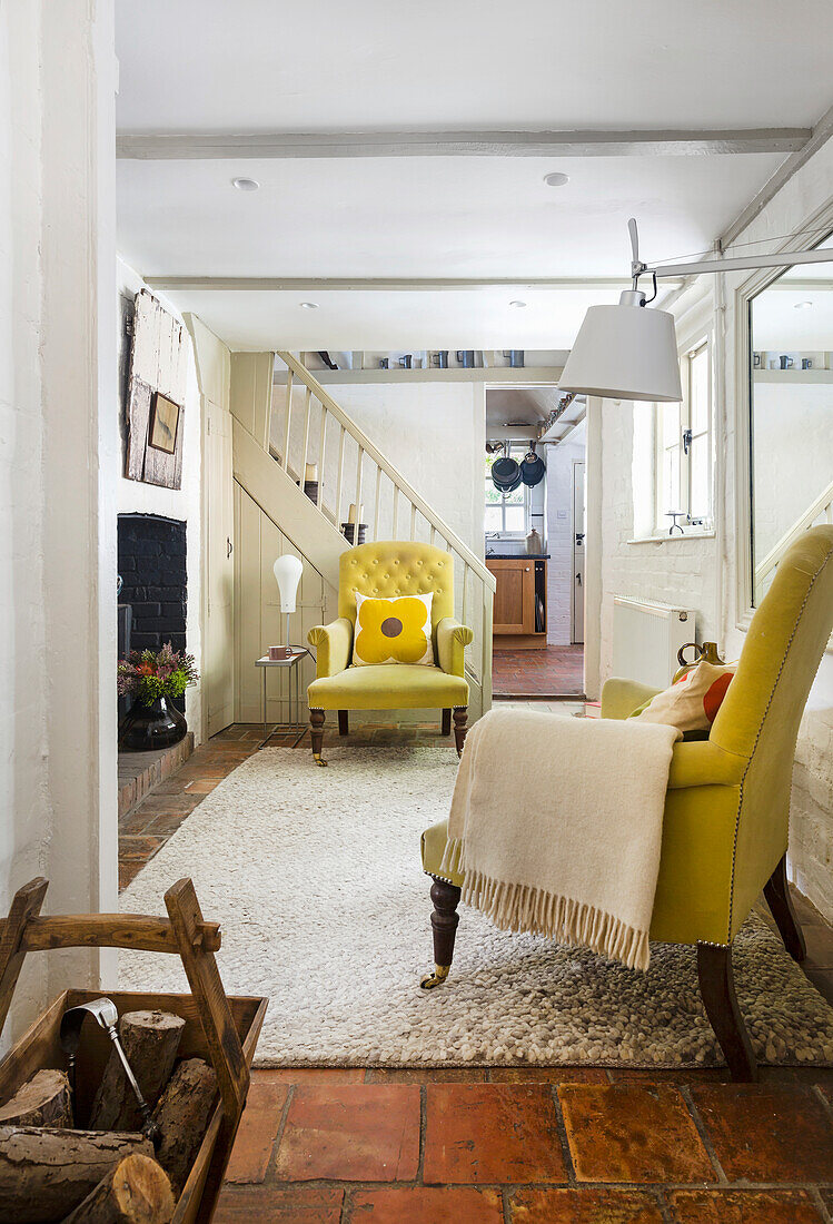 Landhausstil-Wohnzimmer mit Kamin, gelbem Sessel und Terrakotta-Fliesen