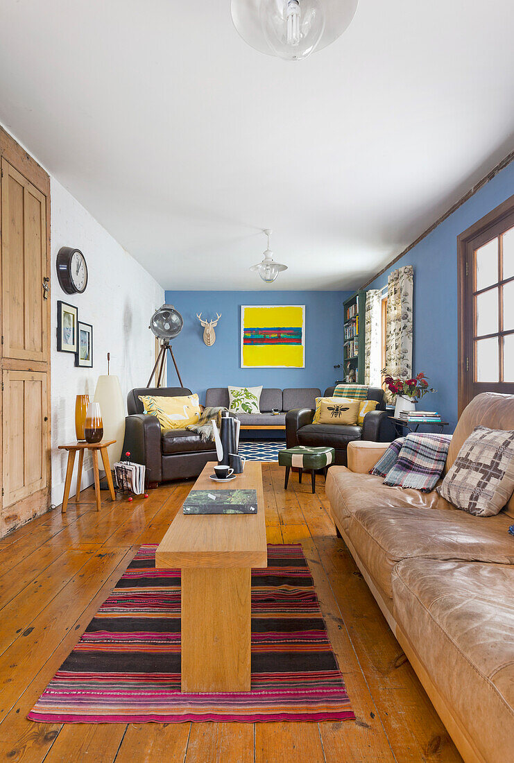 Living room with leather furniture, wooden floor and blue walls