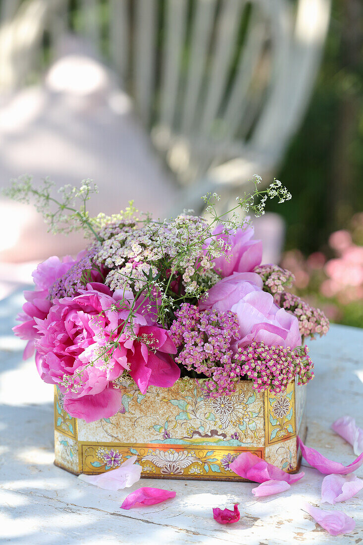 Flowering peonies and historic shrub peonies in nostalgic tin cans