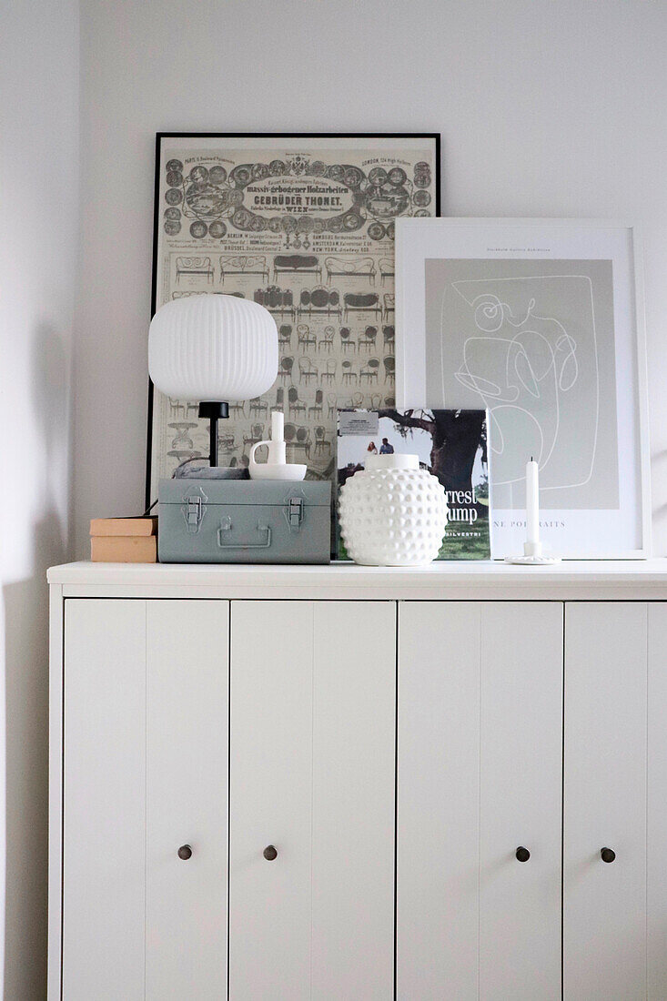 Weißer Sideboard-Schrank mit Dekor und gerahmten Illustrationen