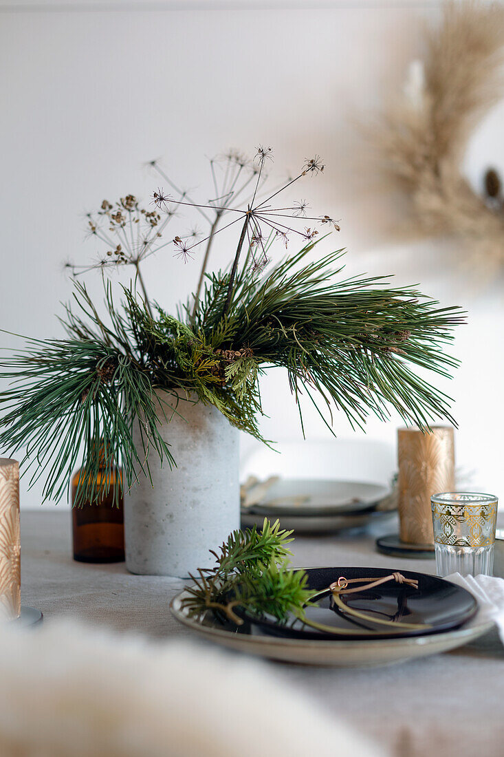 Vase mit Kiefernzweig auf weihnachtlichem Tisch