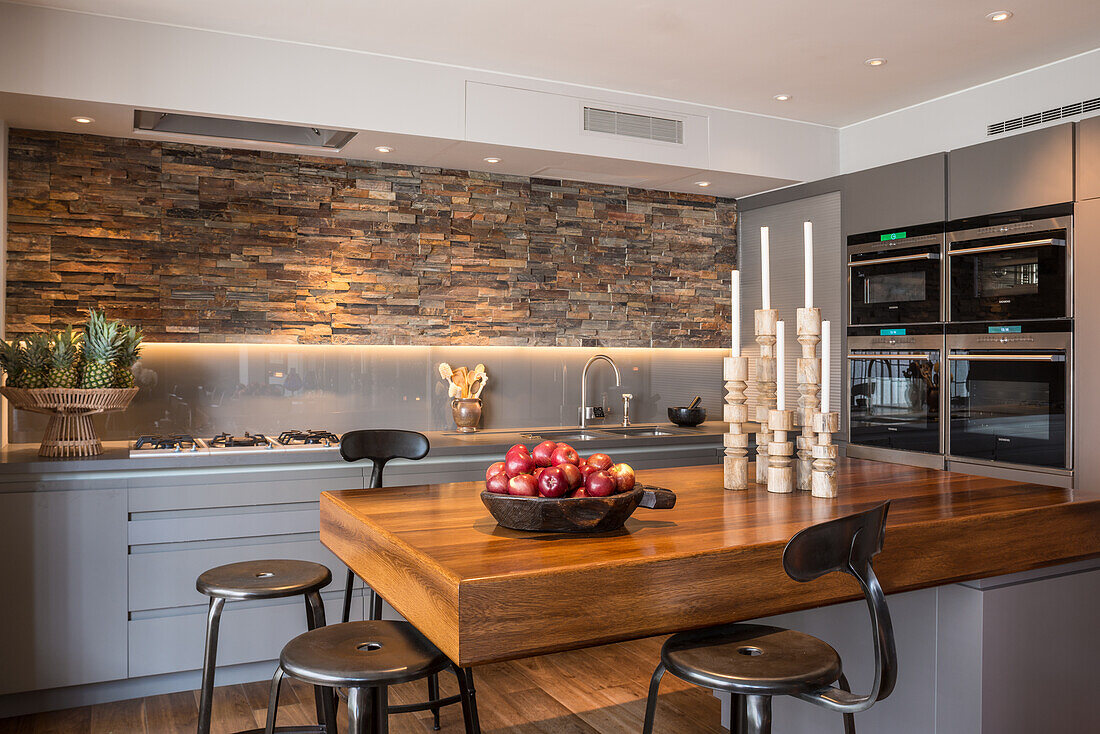 Teak breakfast bar in open-plan kitchen with slate-clad wall