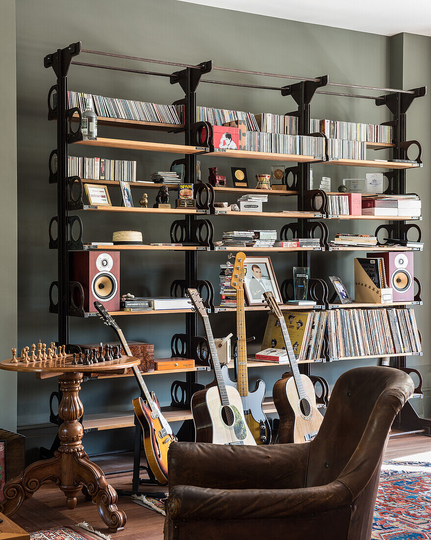 Wall of shelves with CDs, records and speakers, guitars and chess set in the foreground