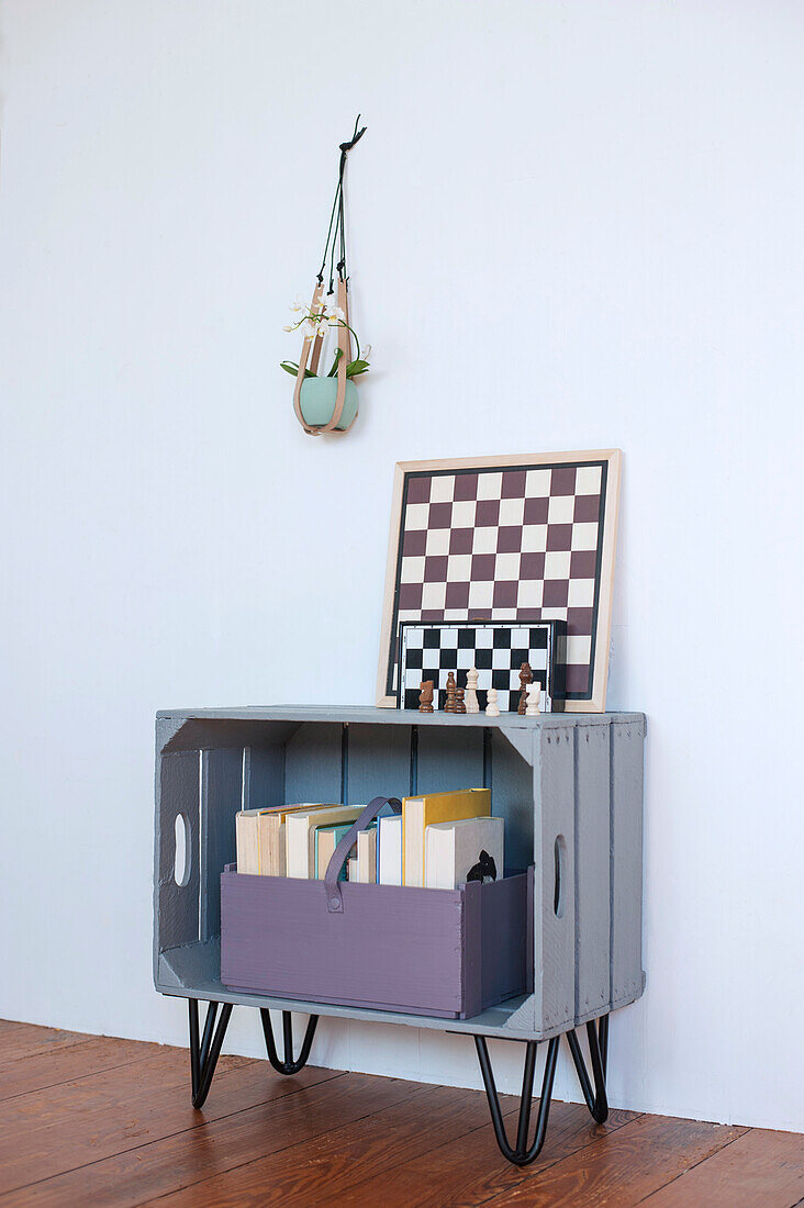 Schachbretter liegen auf einem DIY-Bücherregal aus Holzkiste