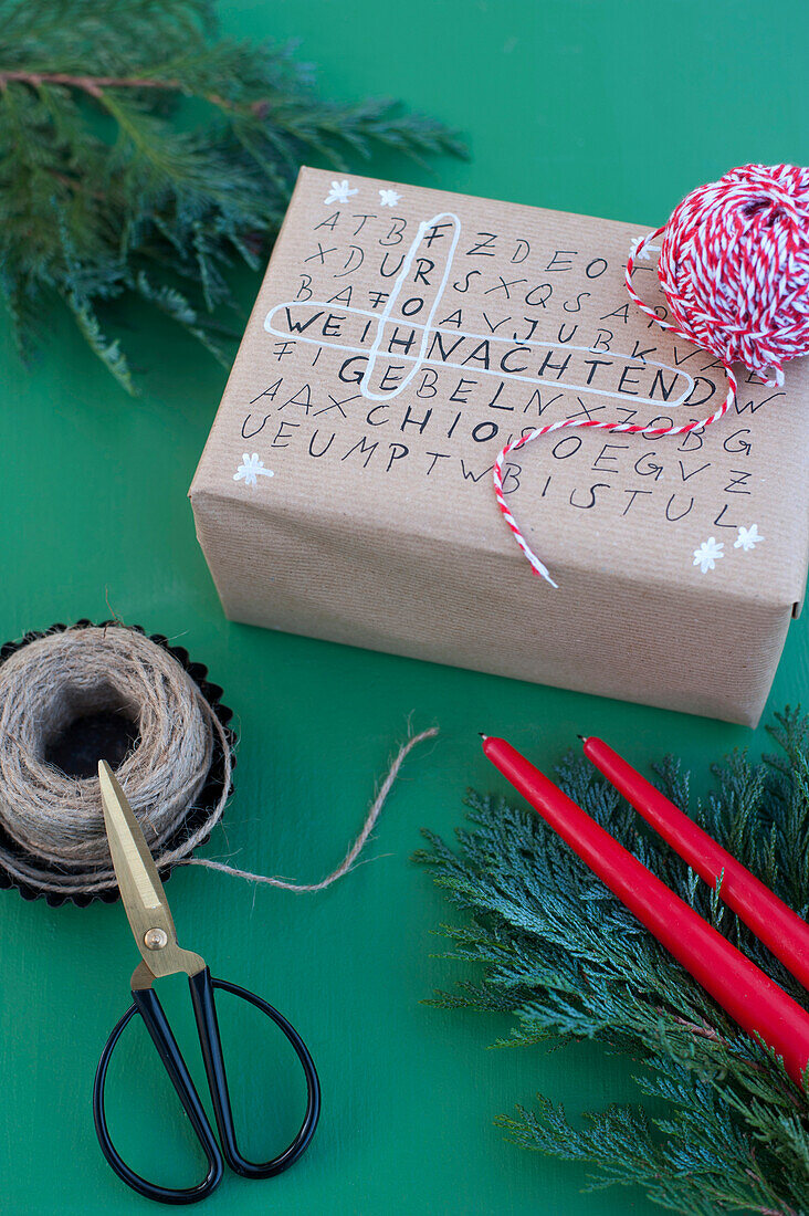 Schere, Schnur und Wortsuchrätsel auf verpacktem Weihnachtsgeschenk