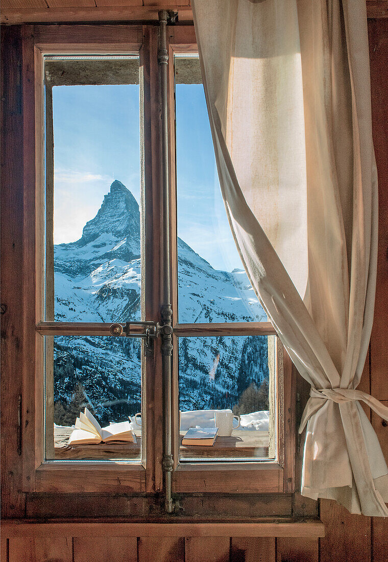 Blick auf den Matterhorn-Gipfel durch ein Fenster mit rustikalem Holzrahmen