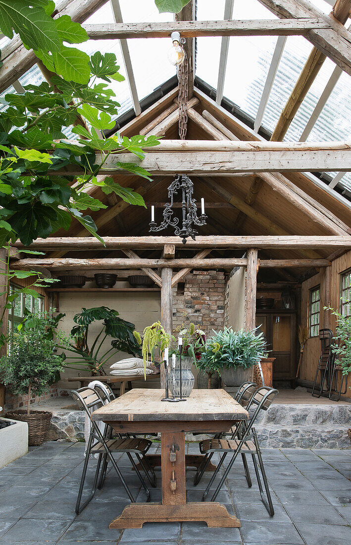 Wooden table with chairs in a renovated barn with a glass roof